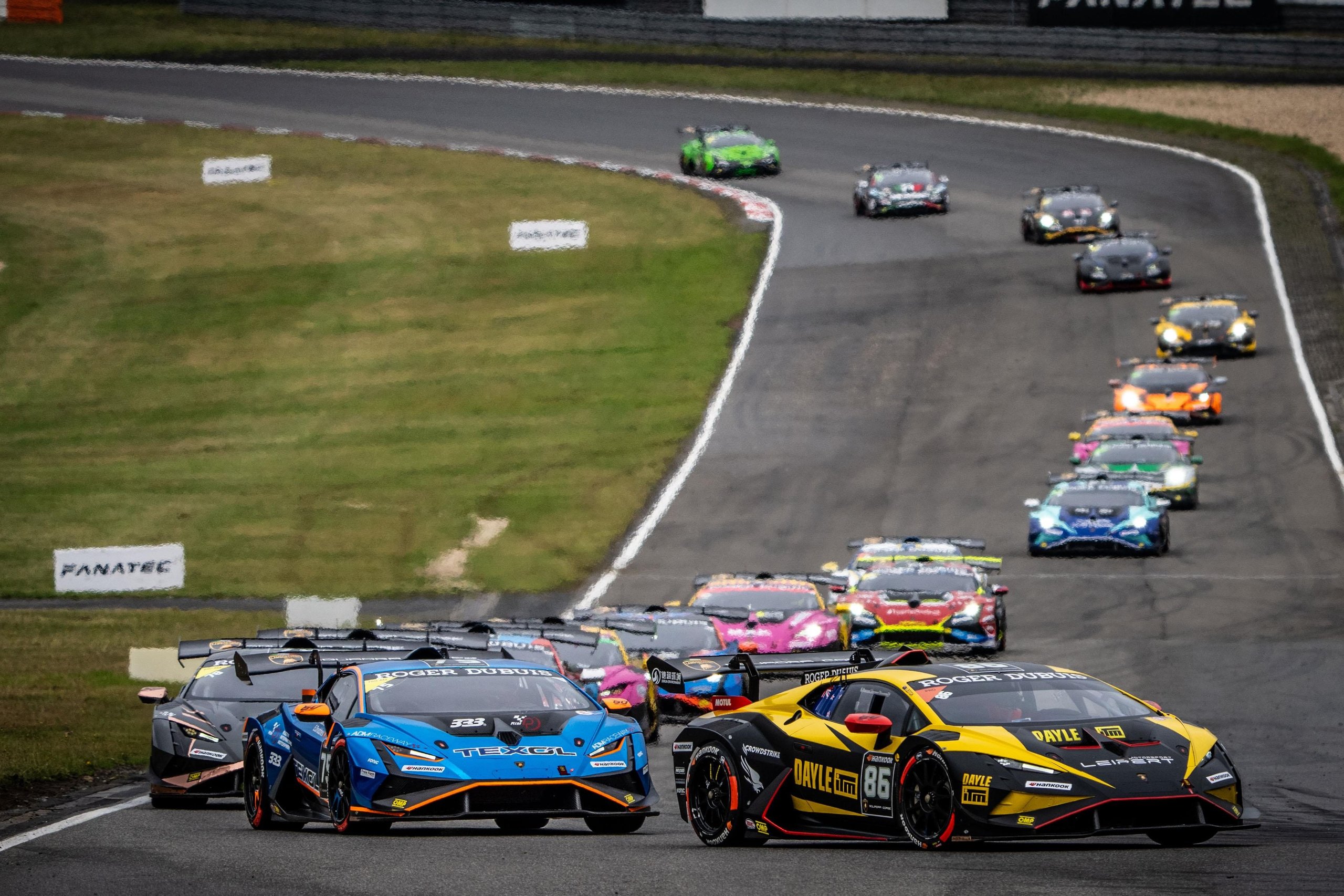 52 Huracán Evo2S At Vallelunga: Why The Super Trofeo'S Record Grid Matters Beyond The Championship Fight 3 Multiple lamborghini huracán super trofeo evo2 race cars ascending a hill on a winding racetrack, demonstrating the depth and competitiveness of the field