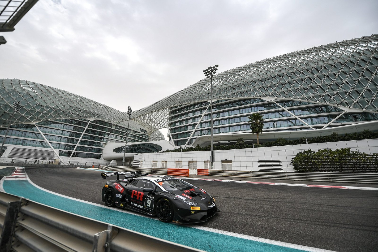 Black Lamborghini Huracán Super Trofeo Evo race car number 9 on track with futuristic buildings in the background