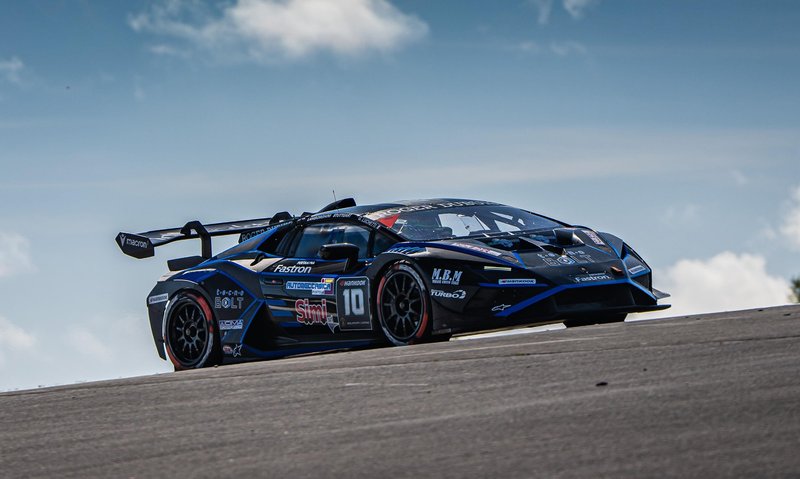 A black Lamborghini Huracán Super Trofeo EVO2 cornering on the Nürburgring circuit under partly cloudy skies