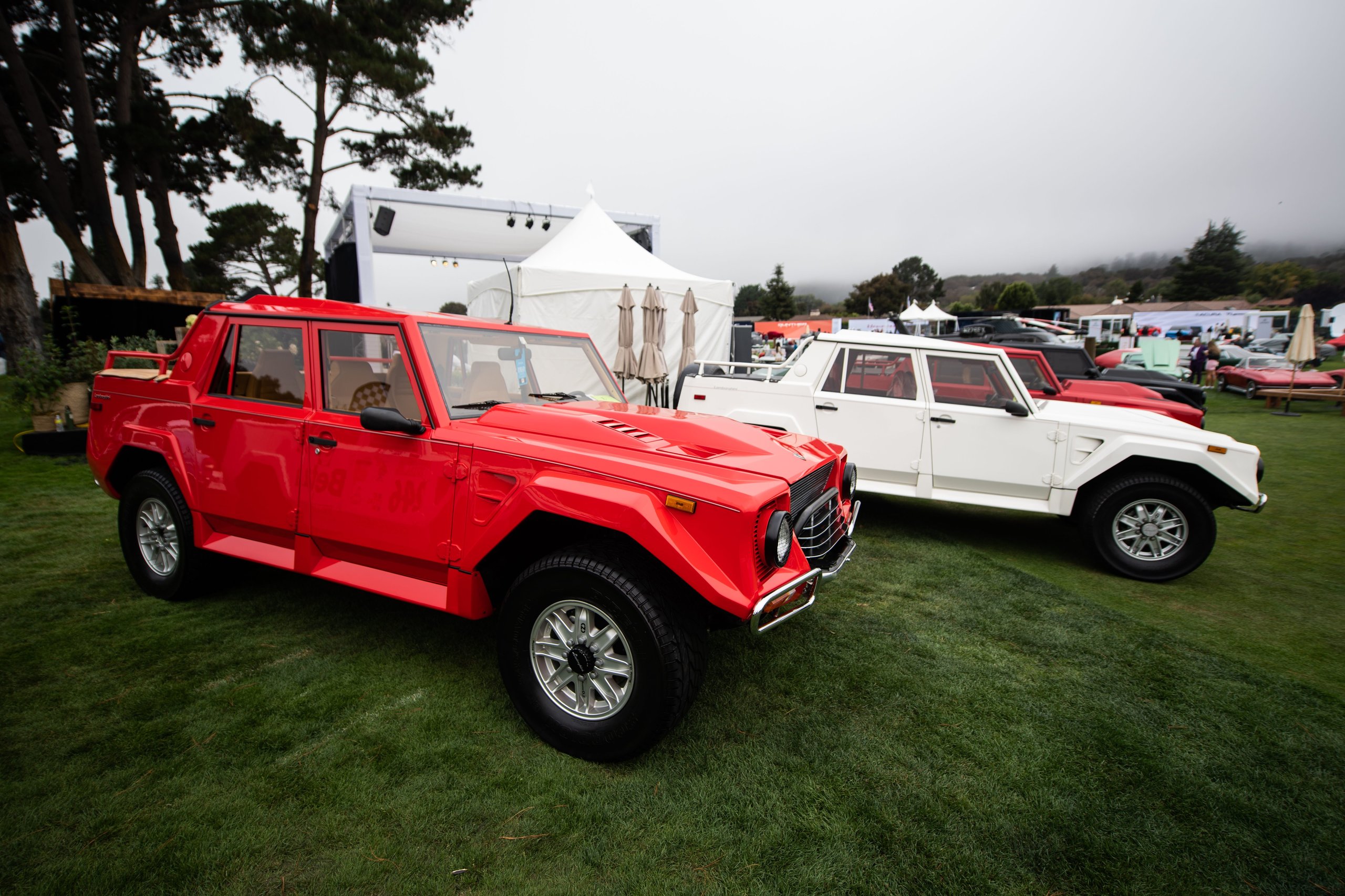 How Lamborghini Turned The Quail Into A Heritage Argument For The Urus Performante 7 Red lamborghini lm002 on the lawn at the quail with a white lm002 and other vehicles in the background