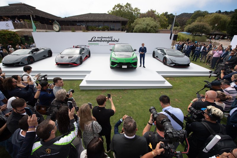 Stephan Winkelmann presents the green Lamborghini Urus Performante on stage at The Quail, flanked by Huracán models and a large crowd