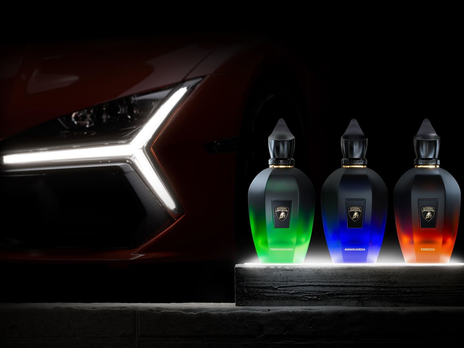 Three Xerjoff x Lamborghini fragrance bottles displayed on an illuminated pedestal with a blurred Lamborghini Revuelto in the background
