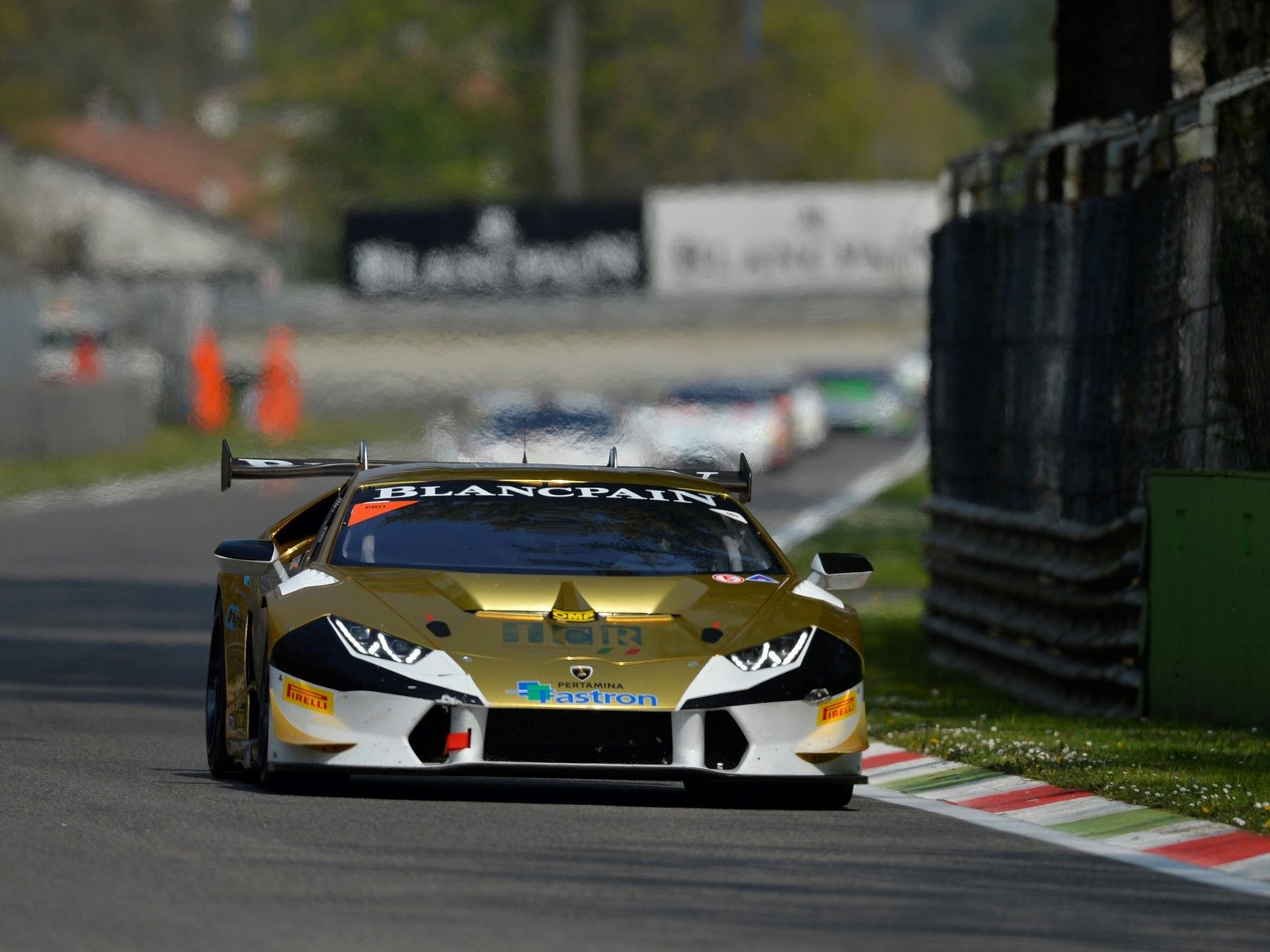 Gold and white Lamborghini Huracán LP 620-2 Super Trofeo racing at speed on track with competitors in the background