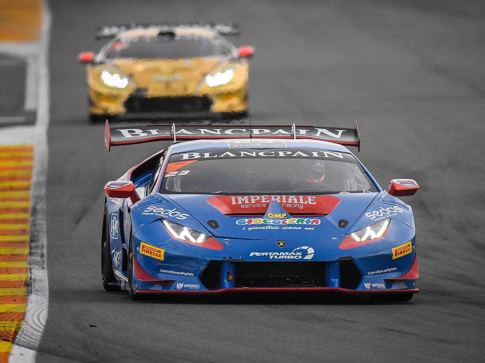 A blue and red Lamborghini Huracán Super Trofeo leads a yellow Huracán through a corner at the 2016 World Final in Valencia