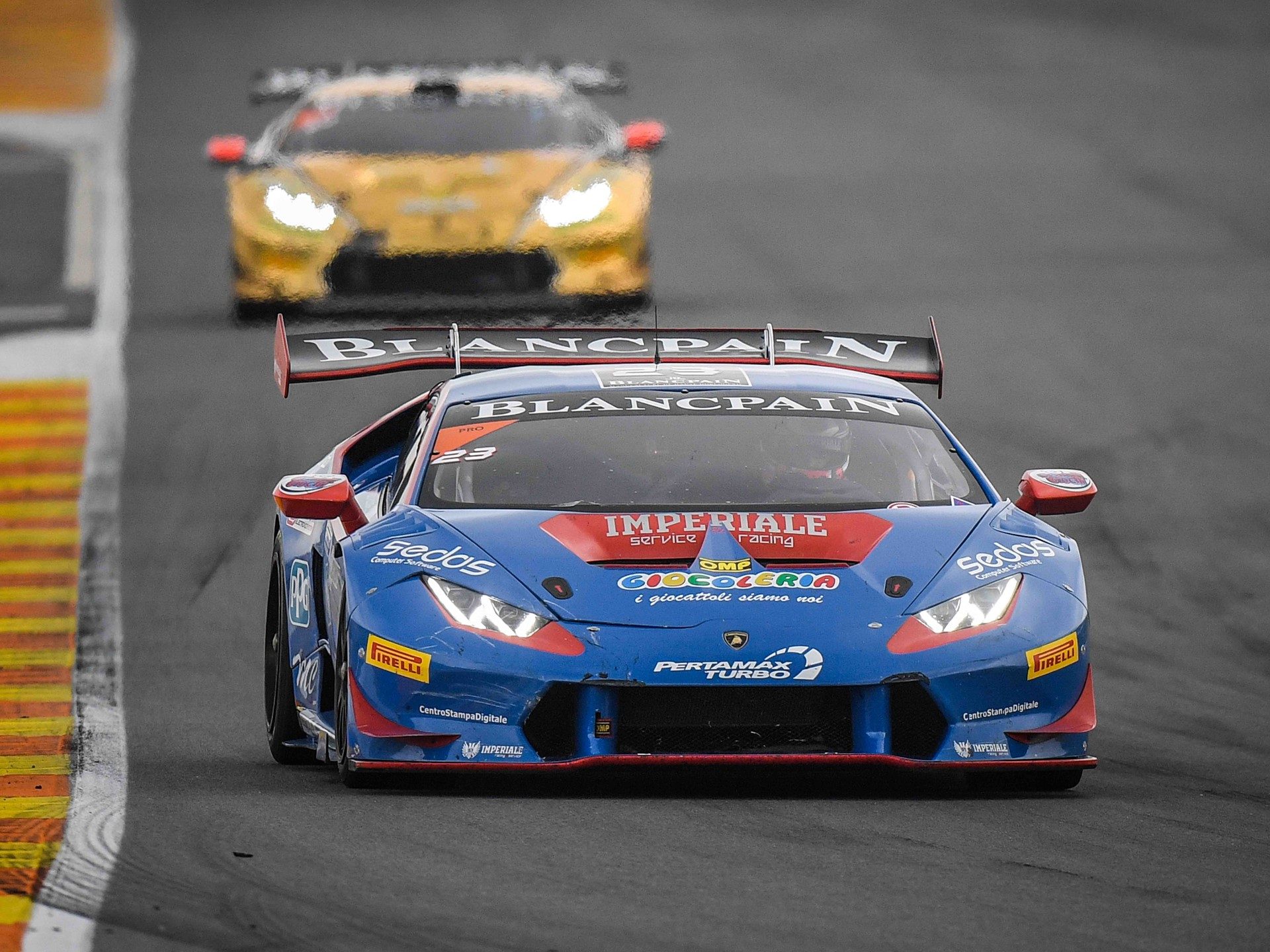 A blue and red Lamborghini Huracán Super Trofeo leads a yellow Huracán through a corner at the 2016 World Final in Valencia