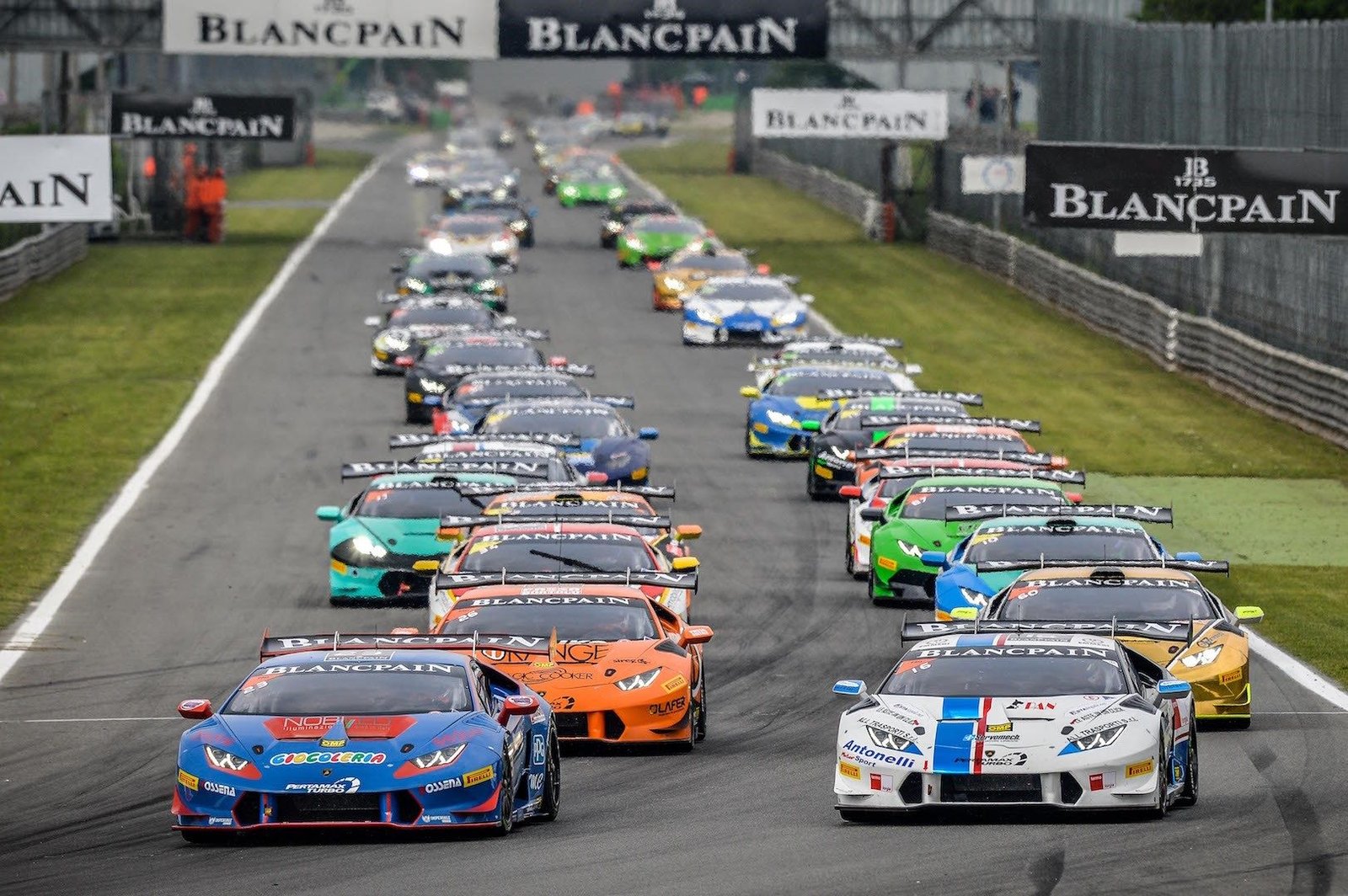 Multiple Lamborghini Huracán Super Trofeo race cars in colorful liveries battling for position on track during the 2016 Blancpain Super Trofeo Europe at Monza