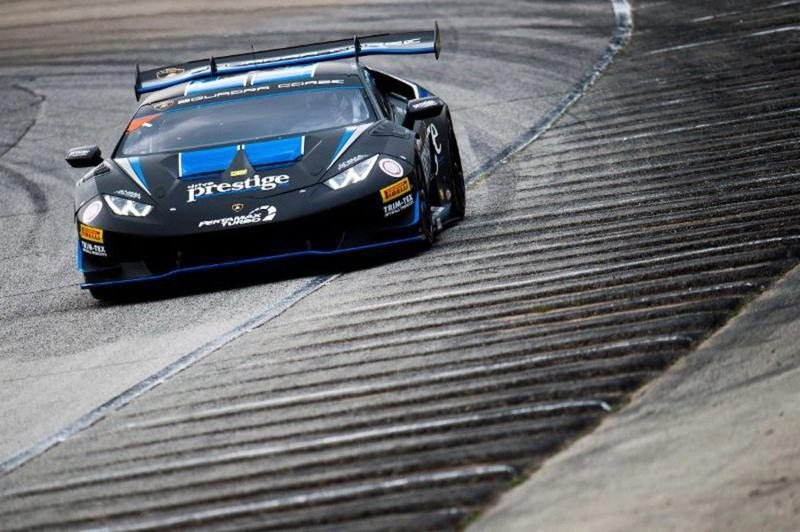 Lamborghini Huracán Super Trofeo race car in black livery with blue accents racing on track, showing the car's aggressive front splitter and large rear wing