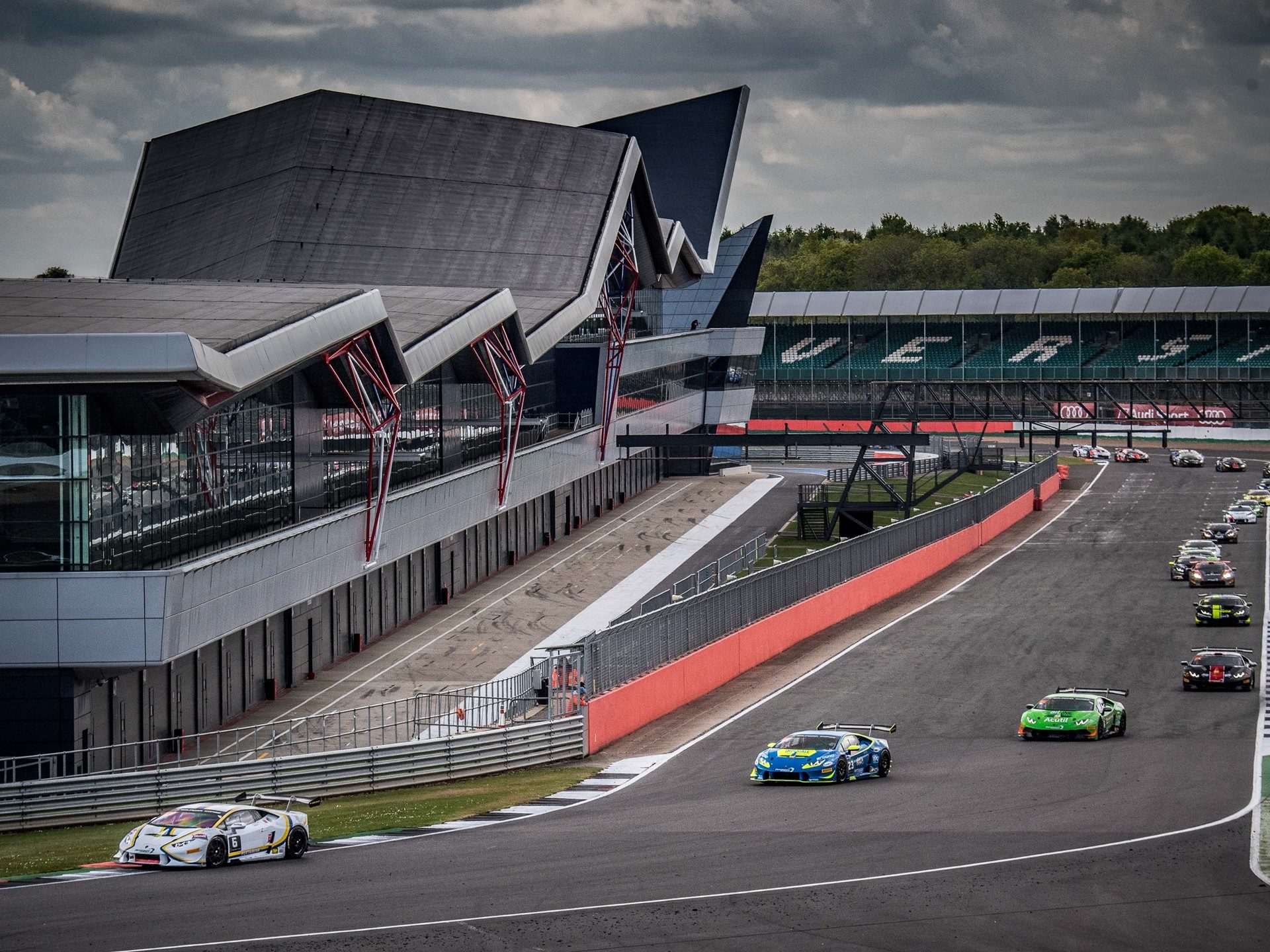 A blue lamborghini huracán super trofeo race car leads a pack through silverstone during the 2017 super trofeo europe round