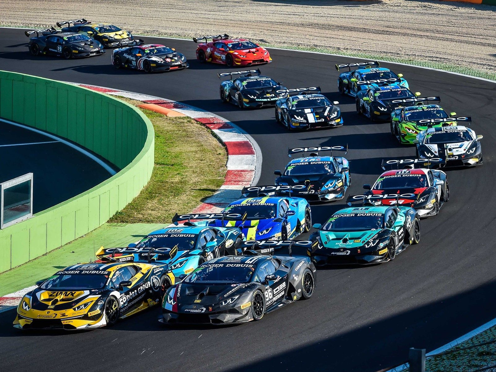 Aerial view of multiple Lamborghini Huracán Super Trofeo race cars in colorful liveries battling for position at Vallelunga during the 2018 World Final