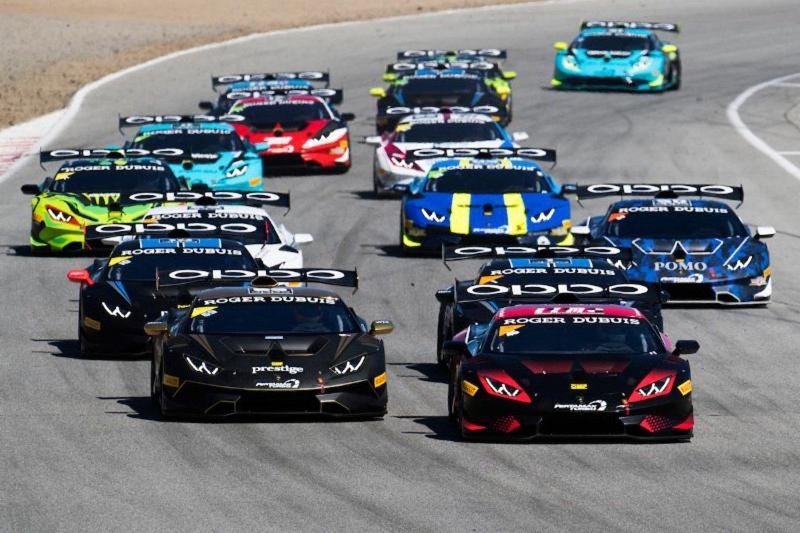 Multiple Lamborghini Huracán Super Trofeo race cars in various liveries battling for position on a racetrack