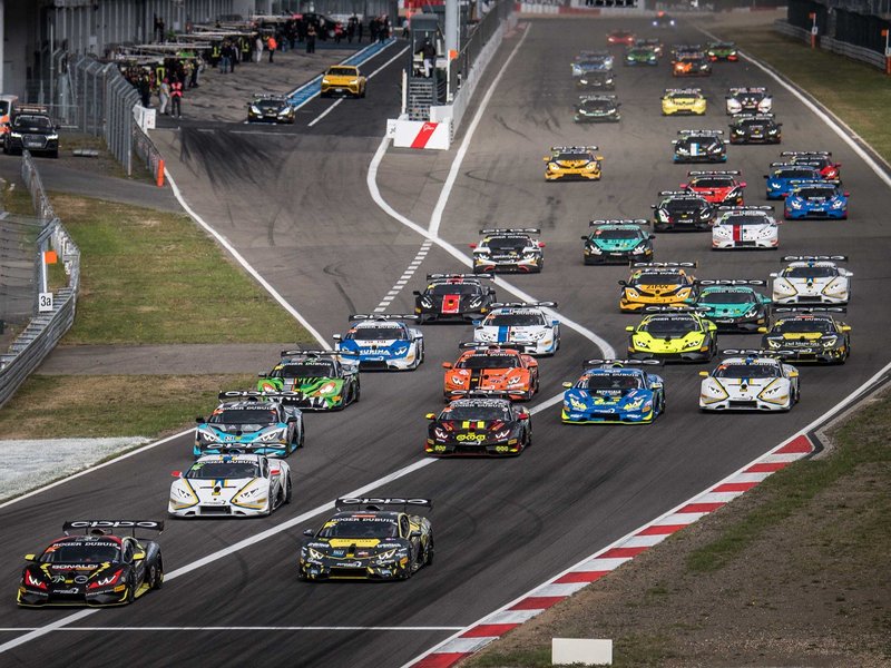 Aerial view of a tightly packed grid of Lamborghini Huracan Super Trofeo Evo race cars in various liveries racing on the Nürburgring circuit