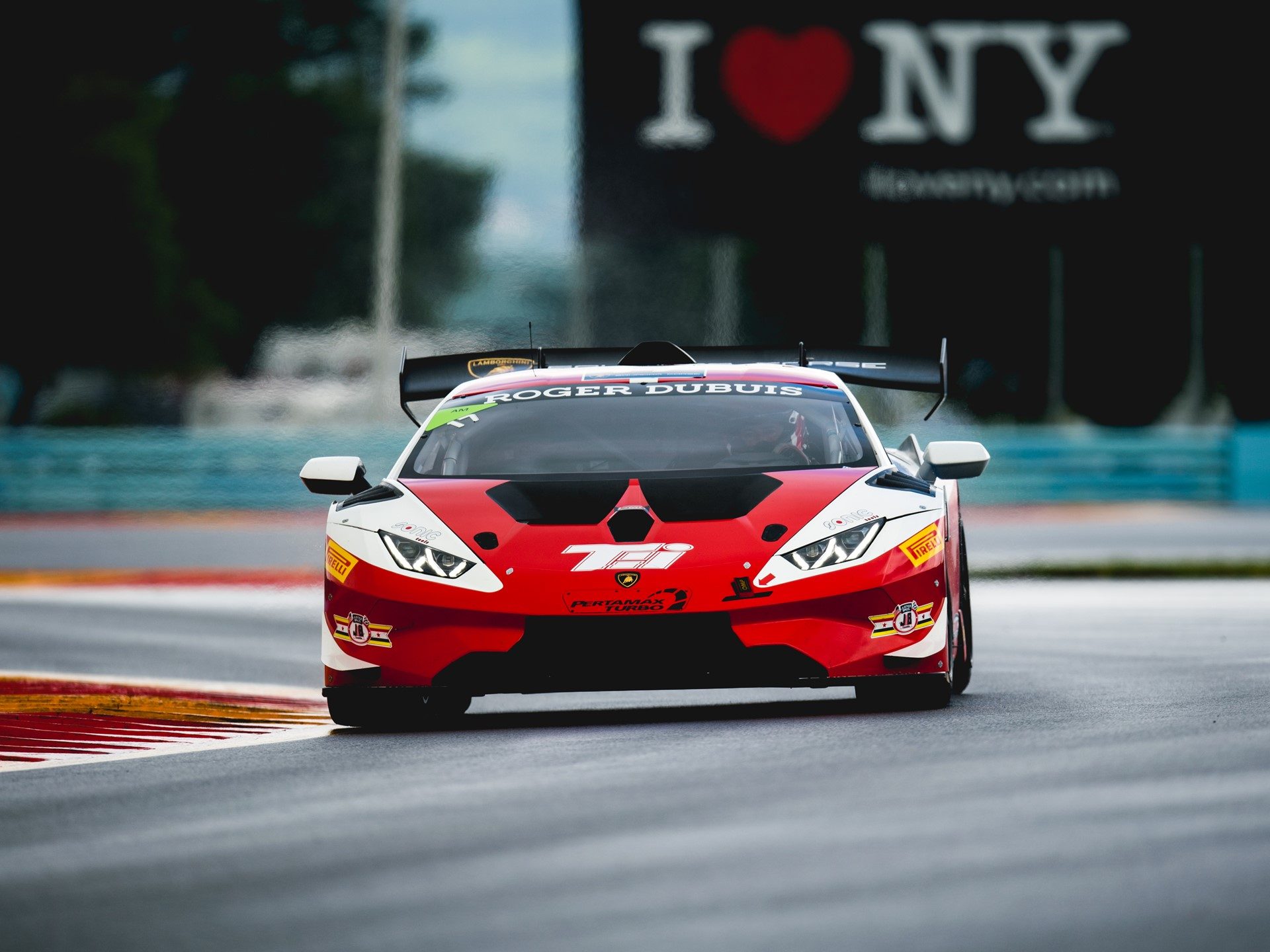 Lamborghini Huracán Super Trofeo Evo race car at speed on track featuring prominent rear wing and racing slicks