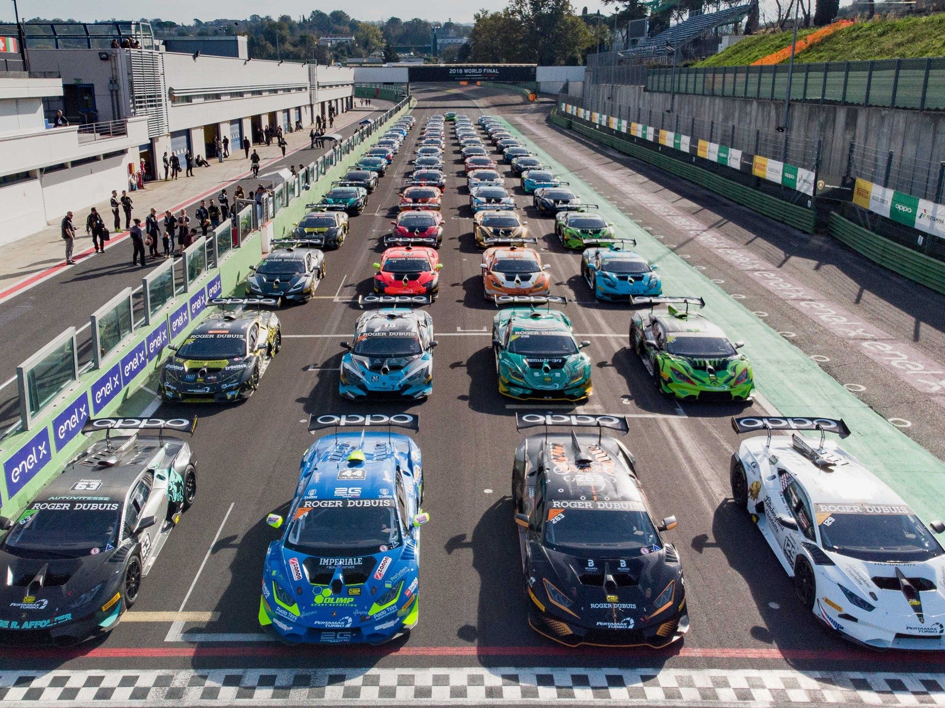 Aerial view of a full grid of Lamborghini Huracán Super Trofeo race cars lined up on a circuit in colorful racing liveries