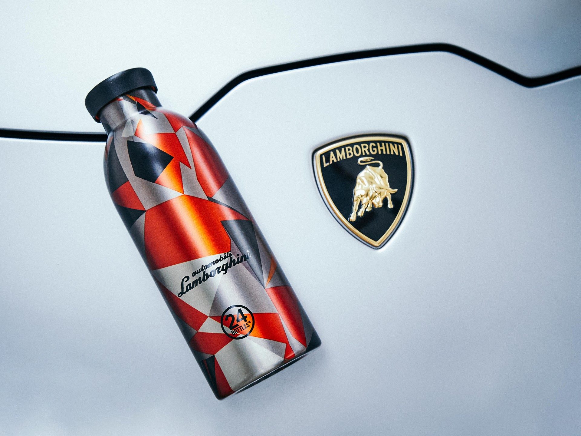 Close-up of 24Bottles Lamborghini Clima Bottle showing geometric red, black, and silver camouflage pattern with Lamborghini logo and gold shield emblem