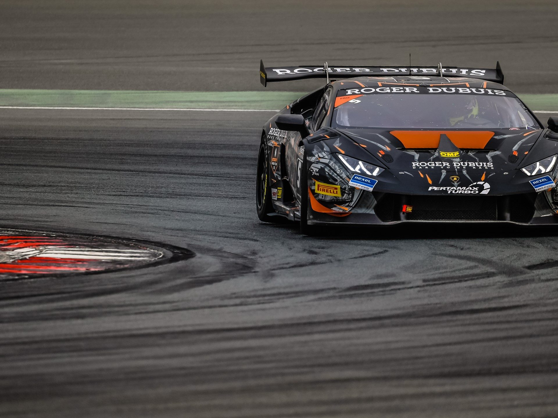 Lamborghini Huracán Super Trofeo race car with aerodynamic body kit and large rear wing navigating a corner at speed