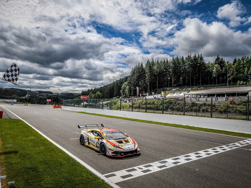 A Lamborghini Huracan Super Trofeo race car crosses the finish line under the checkered flag at Spa-Francorchamps
