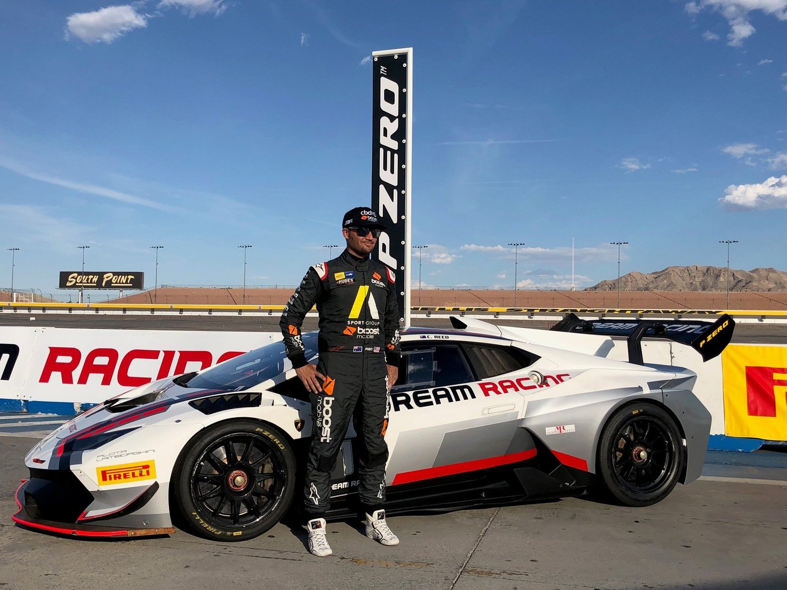 Chad Reed in black and yellow racing suit standing beside a white Lamborghini Huracán Super Trofeo EVO on track