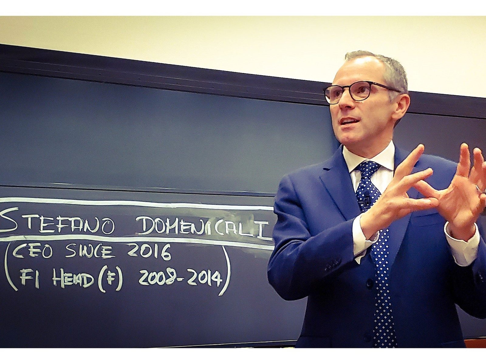 Stefano Domenicali presenting at Harvard Business School with career highlights written on a blackboard