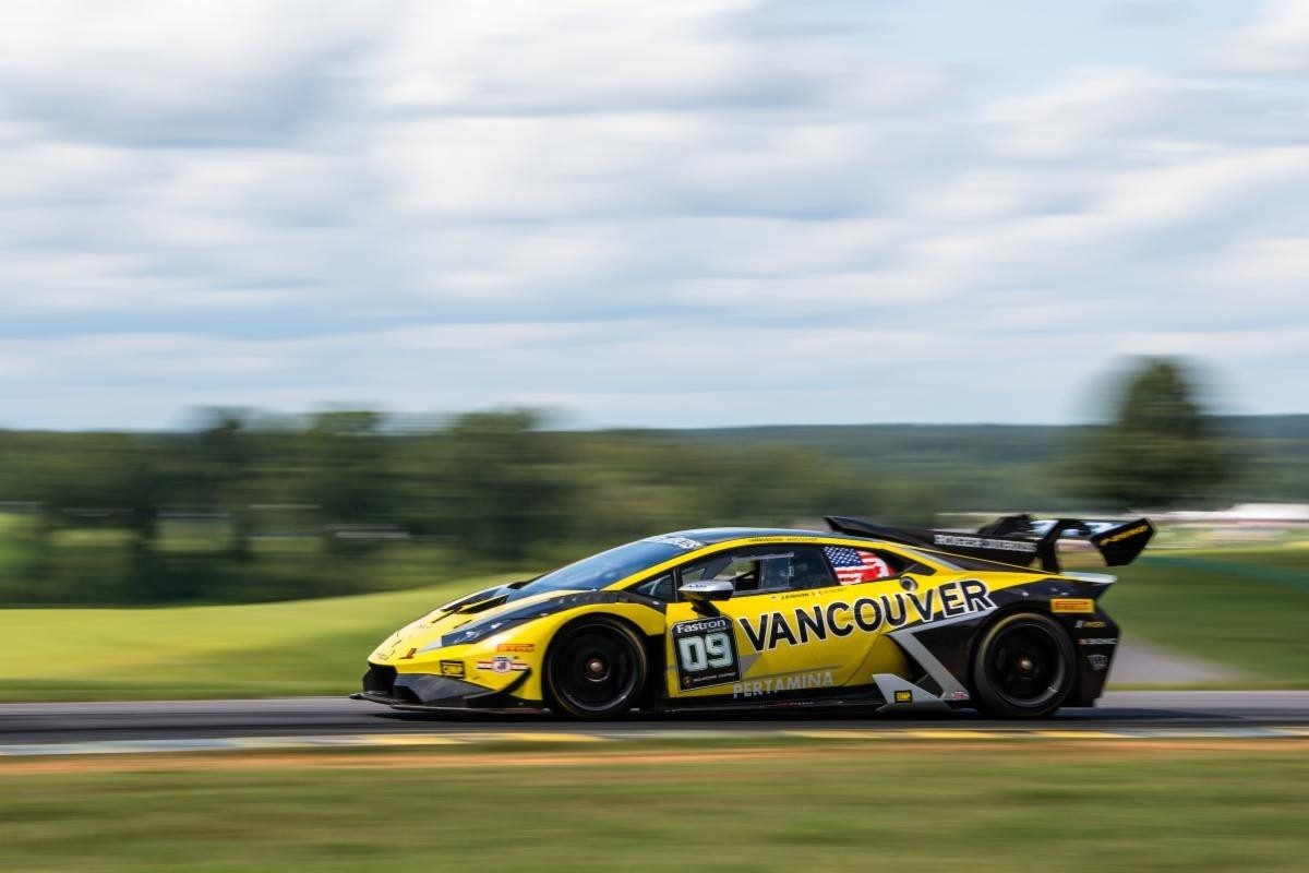 The No. 09 Lamborghini Huracán Evo race car at speed showing its yellow and black livery, large rear wing, and carbon fiber aerodynamic elements