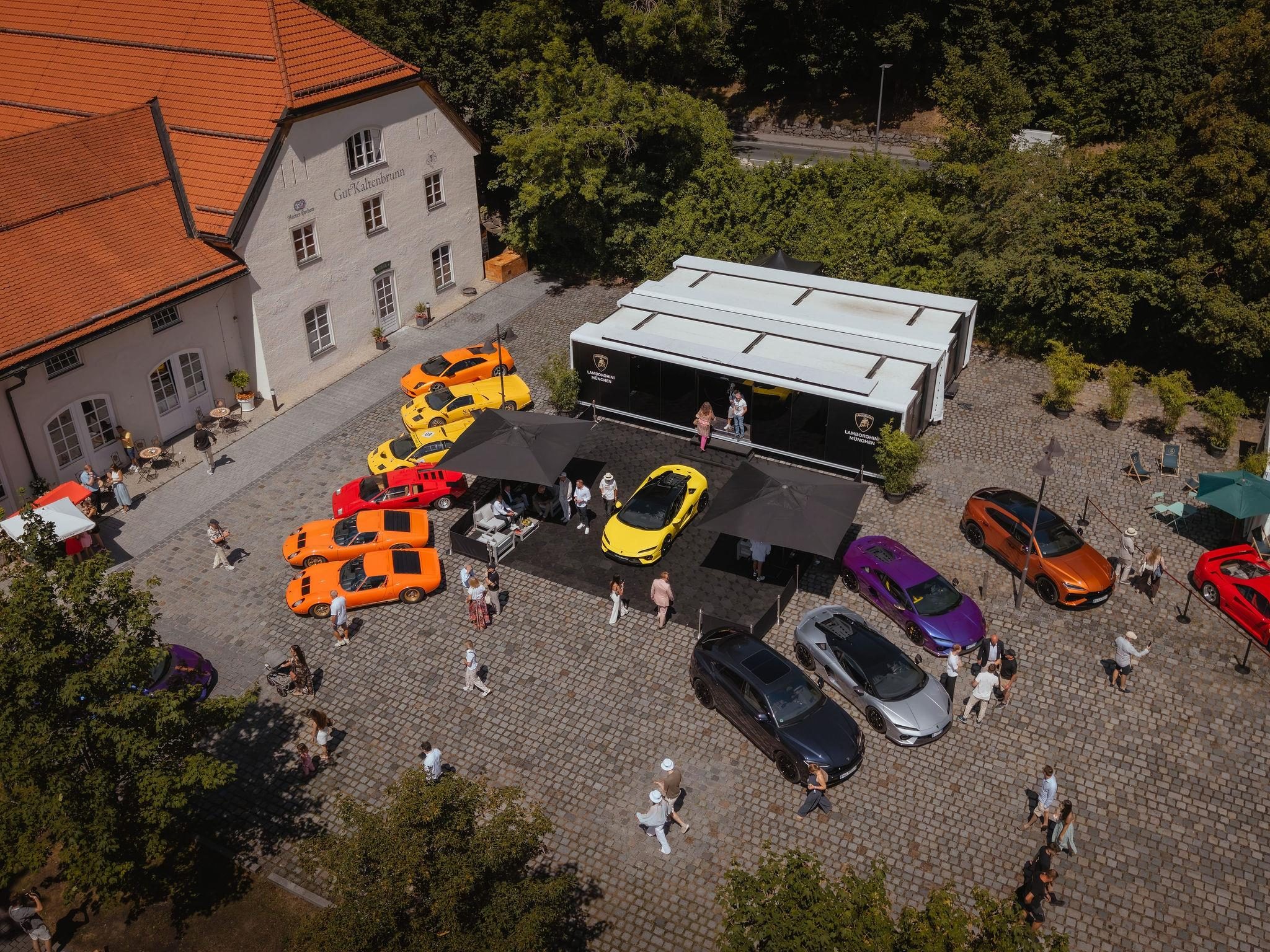 Fenomeno Roadster At Lake Tegernsee: Why Lamborghini Chose A Concours Lawn Over A Motor Show Stage 13 Aerial view of the lamborghini display at concours of elegance germany showing multiple models in various colors on cobblestone with tents and historic buildings