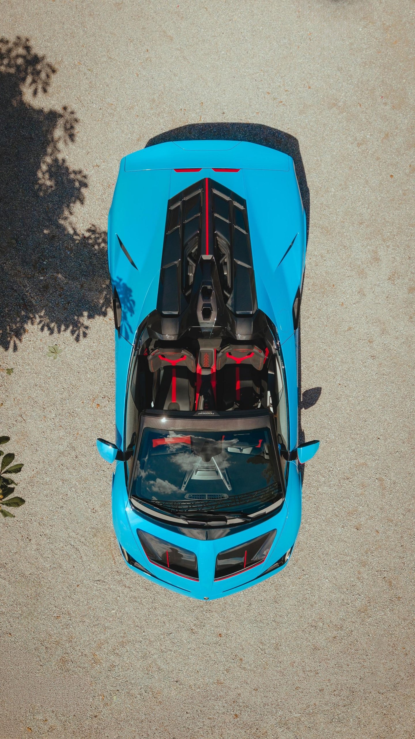 Fenomeno Roadster At Lake Tegernsee: Why Lamborghini Chose A Concours Lawn Over A Motor Show Stage 7 Aerial view of blue and red lamborghini fenomeno roadster showing open-top design, engine cover details, and red interior accents