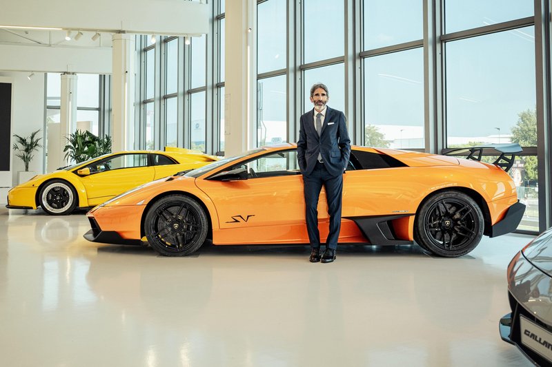 Francesco Milicia, Lamborghini's new Marketing Director, standing between an orange Murciélago SV and a yellow Diablo in the brand's showroom
