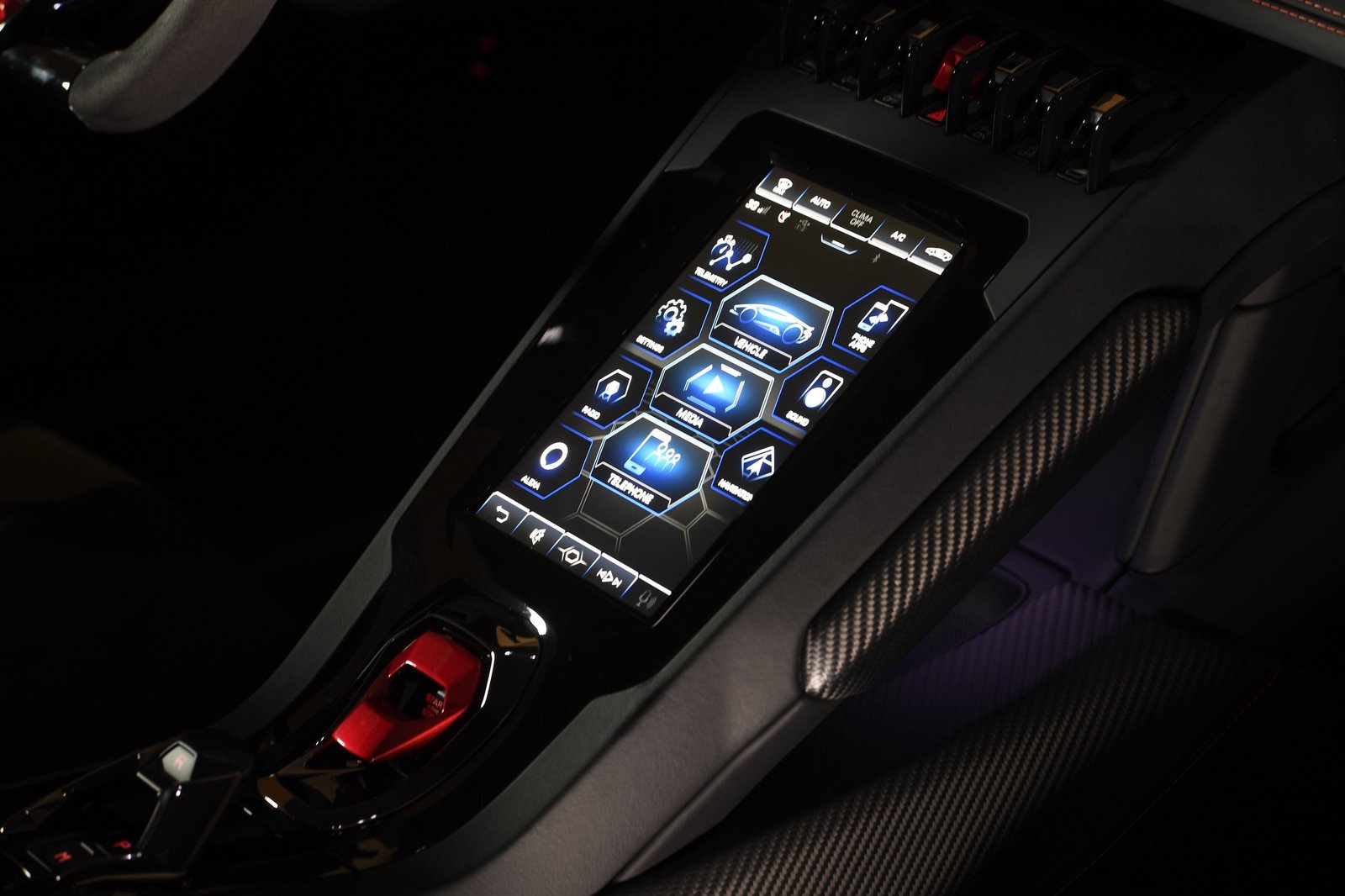 Lamborghini Huracán EVO center console showing the HMI touchscreen with hexagonal menu icons, red start/stop button, and carbon fiber trim