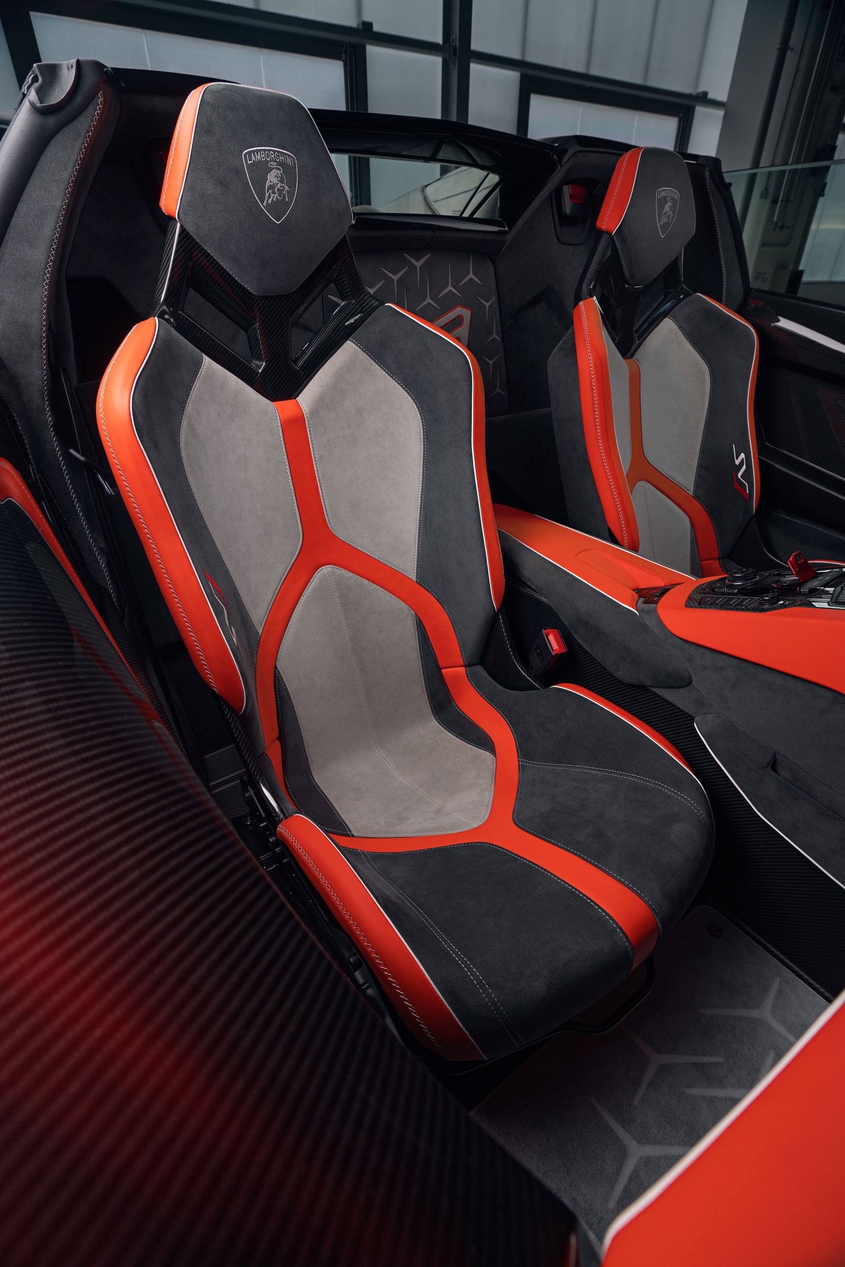 Interior of the aventador svj 63 roadster showing tri-tone alcantara upholstery in grey and orange with carbon fiber elements
