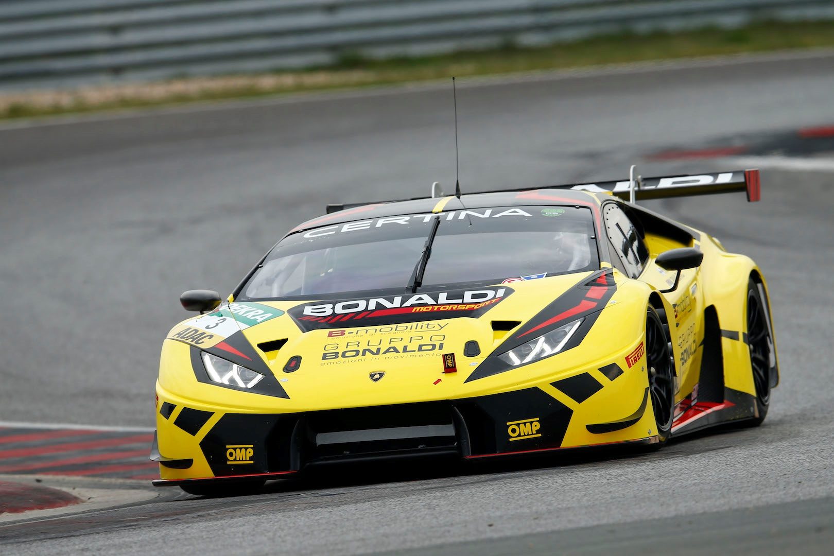 Yellow lamborghini huracán gt3 racing on a wet track, showing aggressive front splitter and aerodynamic bodywork