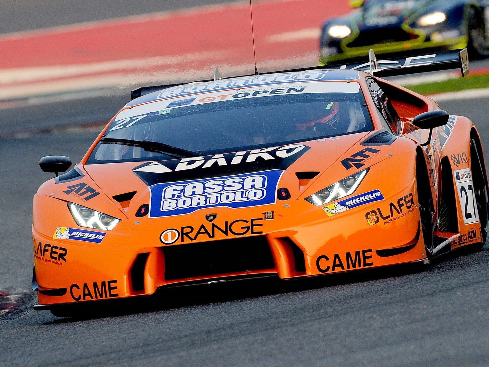 Orange Lamborghini Huracán GT3 race car with sponsor decals at speed on a circuit during the 2016 International GT Open season