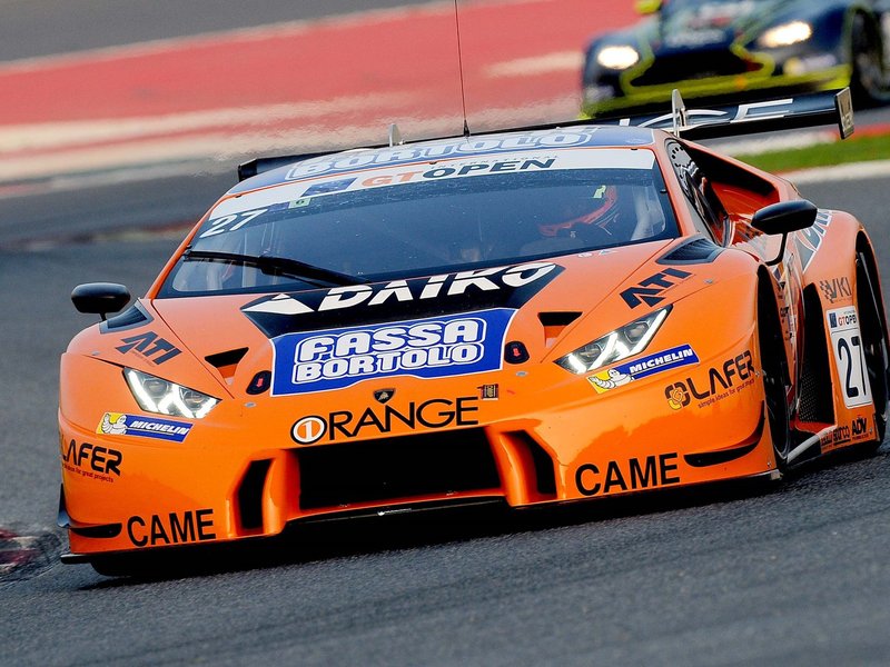 Orange Lamborghini Huracán GT3 race car with sponsor decals at speed on a circuit during the 2016 International GT Open season