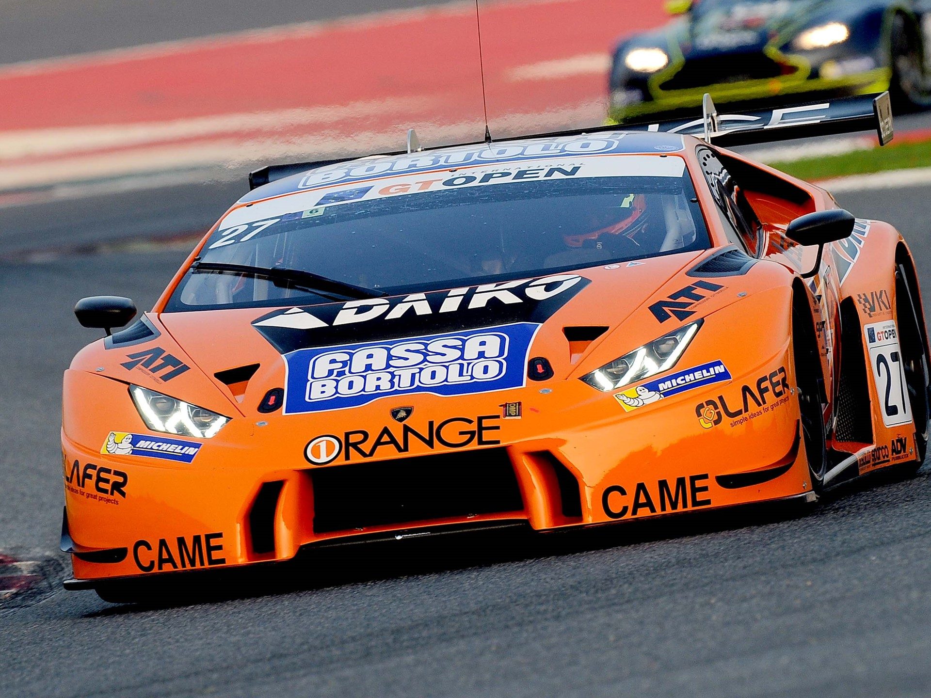 Orange lamborghini huracán gt3 race car with sponsor decals at speed on a circuit during the 2016 international gt open season