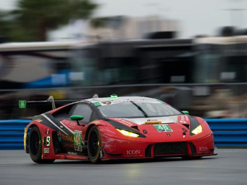 Lamborghini Huracán GT3 race car in red and black livery at speed on a racing circuit