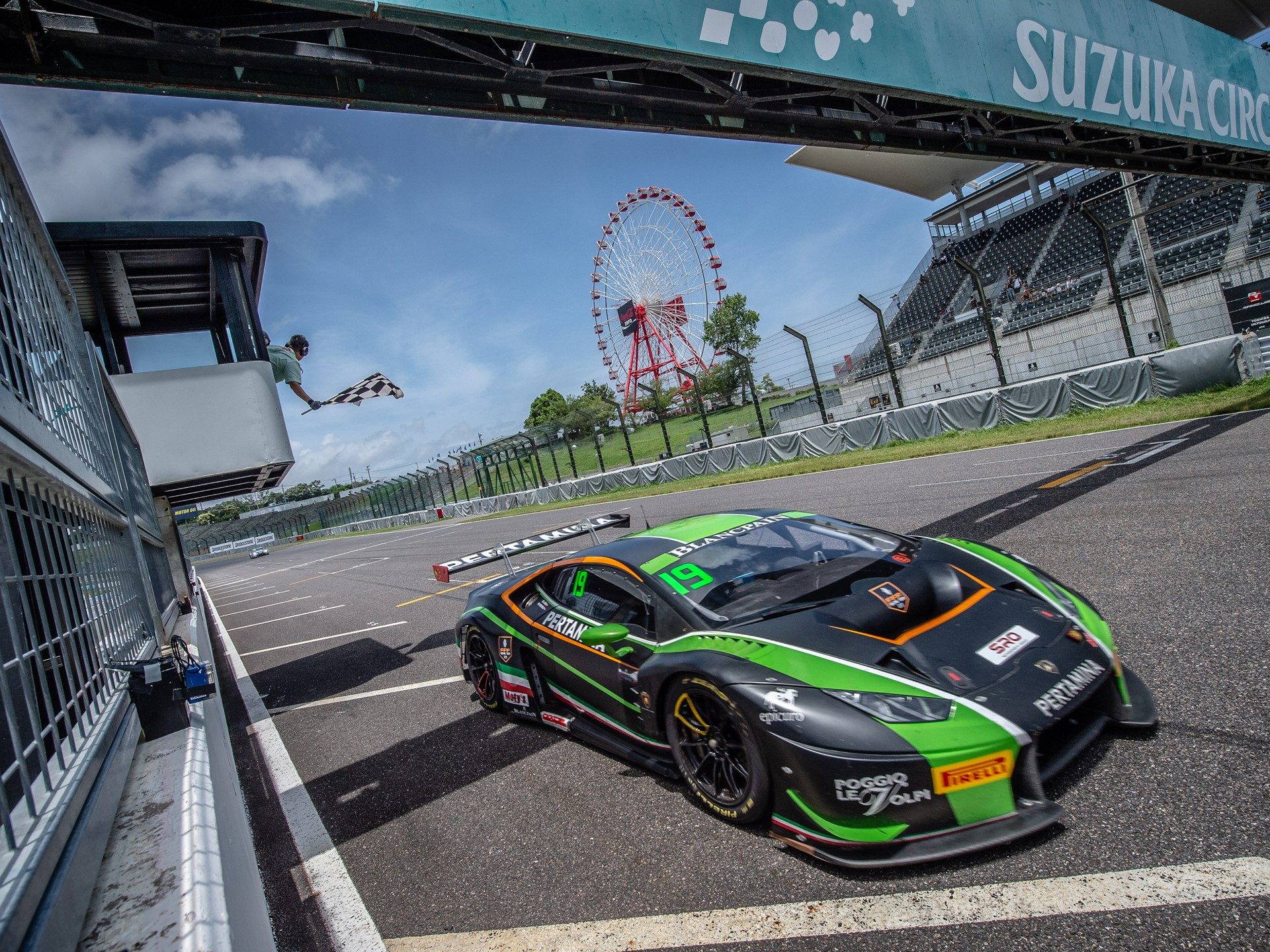 Black and green Lamborghini Huracán GT3 race car crossing the finish line under a checkered flag