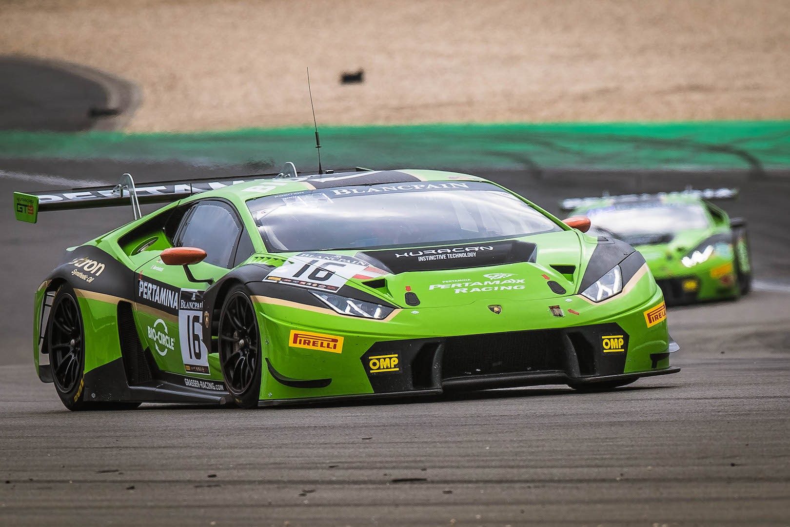 Green Lamborghini Huracán GT3 race car in full racing livery speeding around a circuit during the Blancpain GT Series Endurance Cup