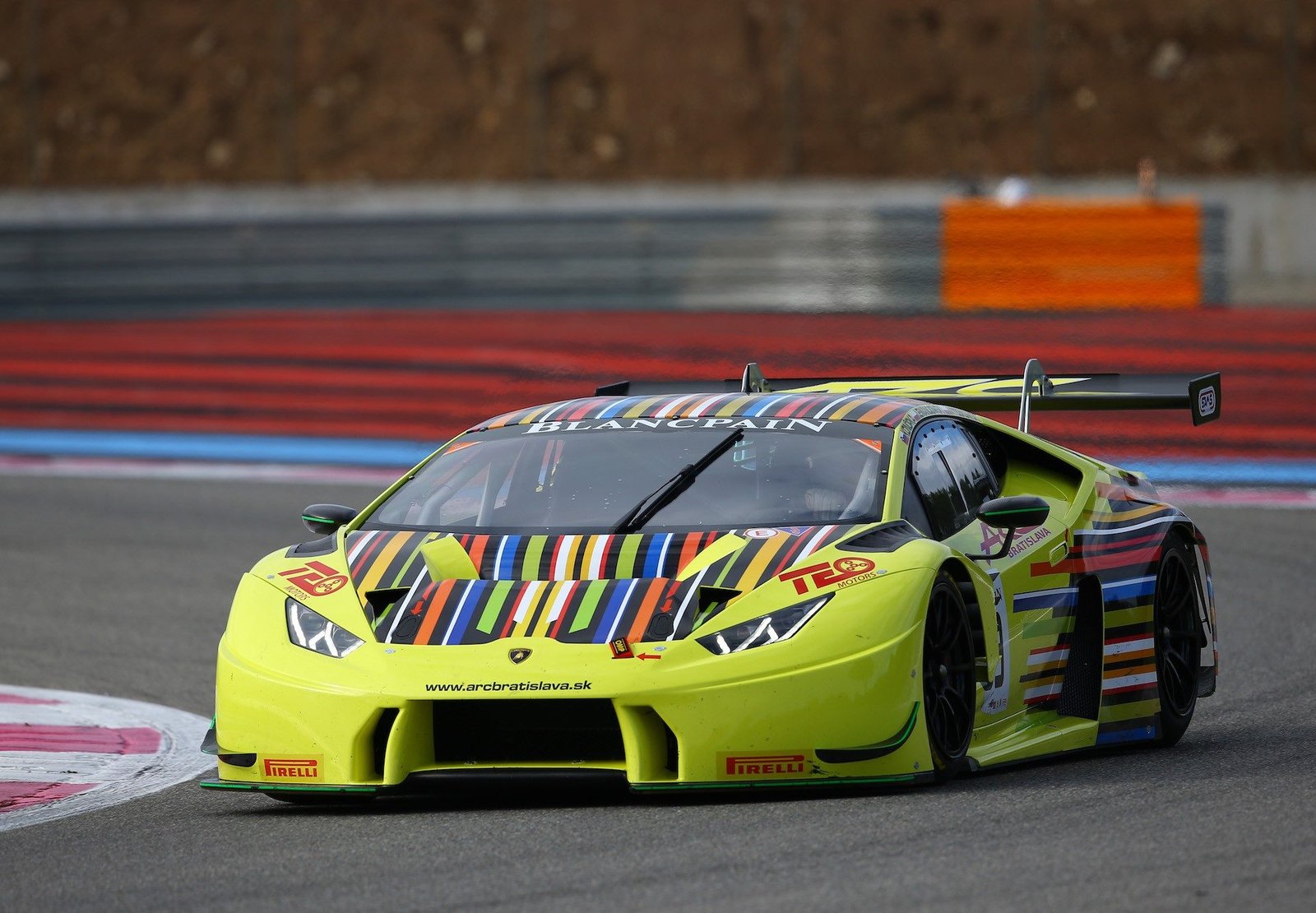 Yellow Lamborghini Huracán GT3 race car with multi-colored striped livery at speed on a racetrack during the 2016 Blancpain GT Series test days
