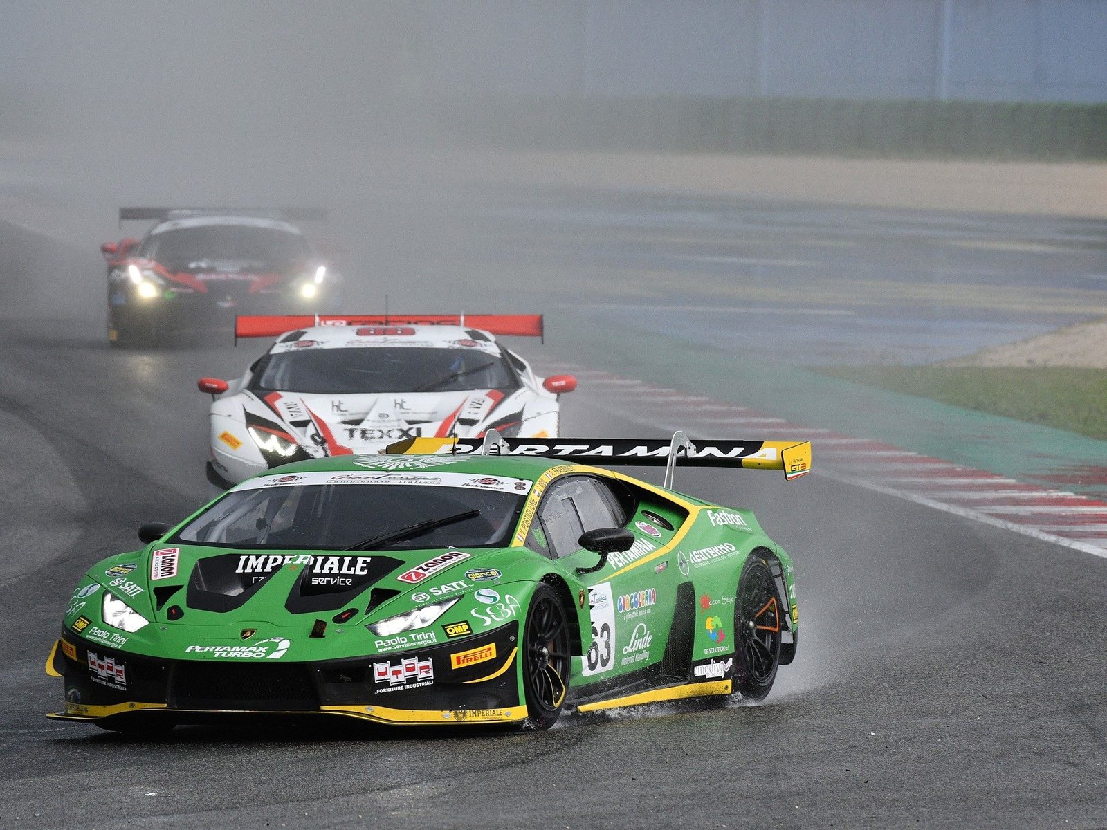 Green Lamborghini Huracán GT3 EVO leads competitors on a wet race track during a GT championship event