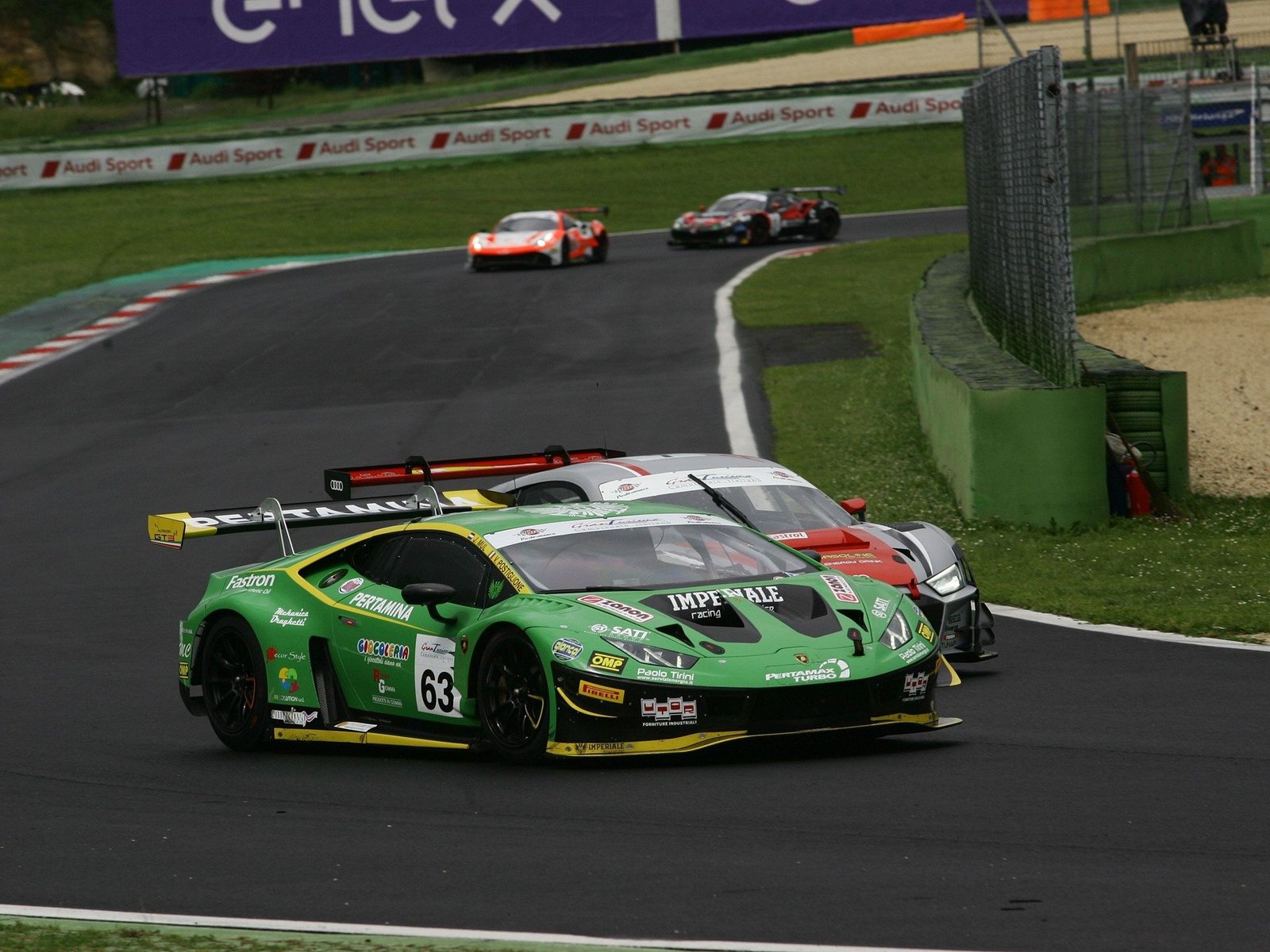 Green Lamborghini Huracán GT3 EVO number 63 racing on track ahead of an Audi R8 LMS GT3