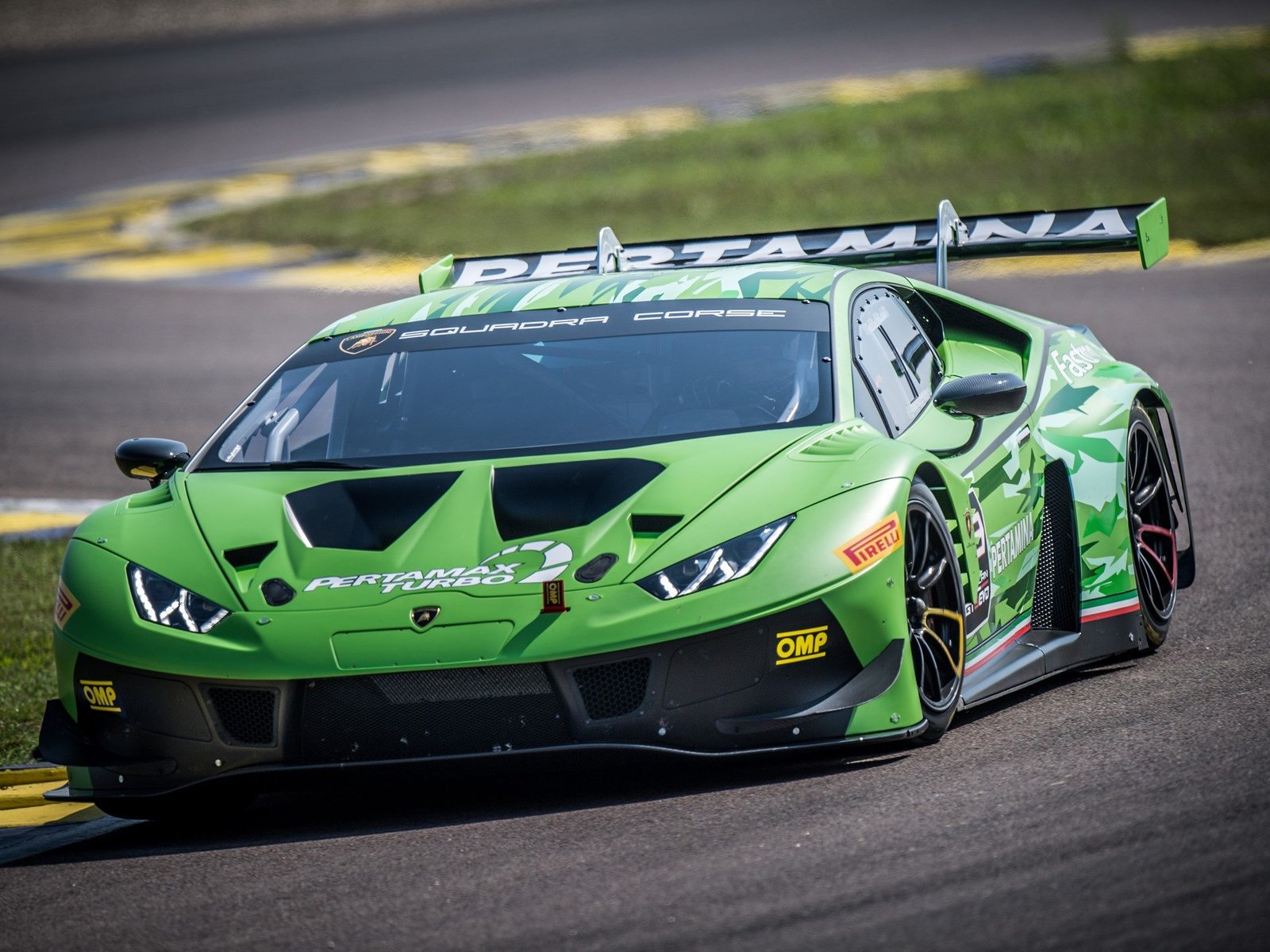 Lamborghini Huracán GT3 EVO in green camouflage livery racing on track, showing aggressive front aero and large rear wing