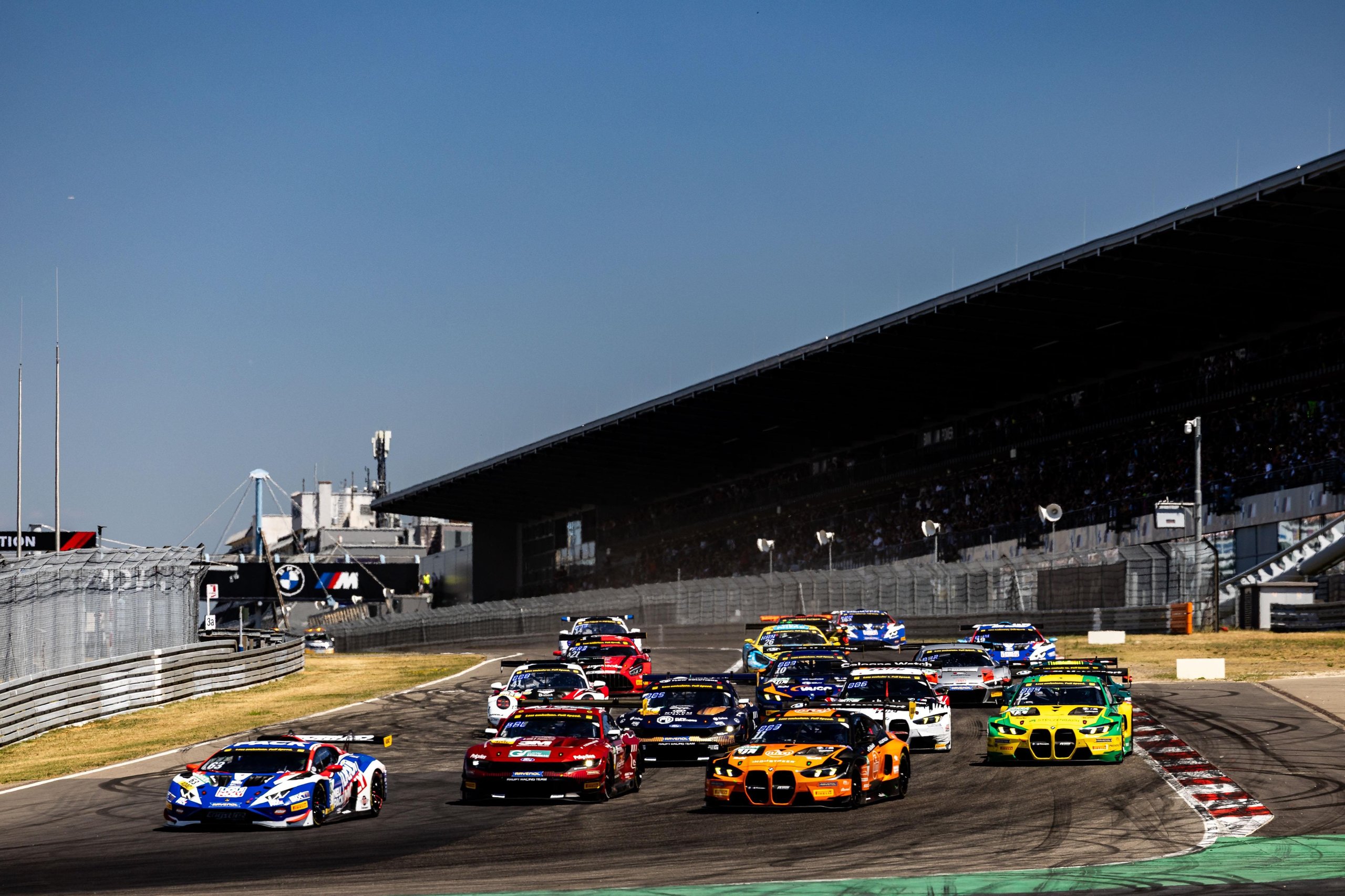 Multiple gt3 race cars including lamborghini huracán gt3 evo2 entries navigate a turn at the nürburgring with spectators in grandstands