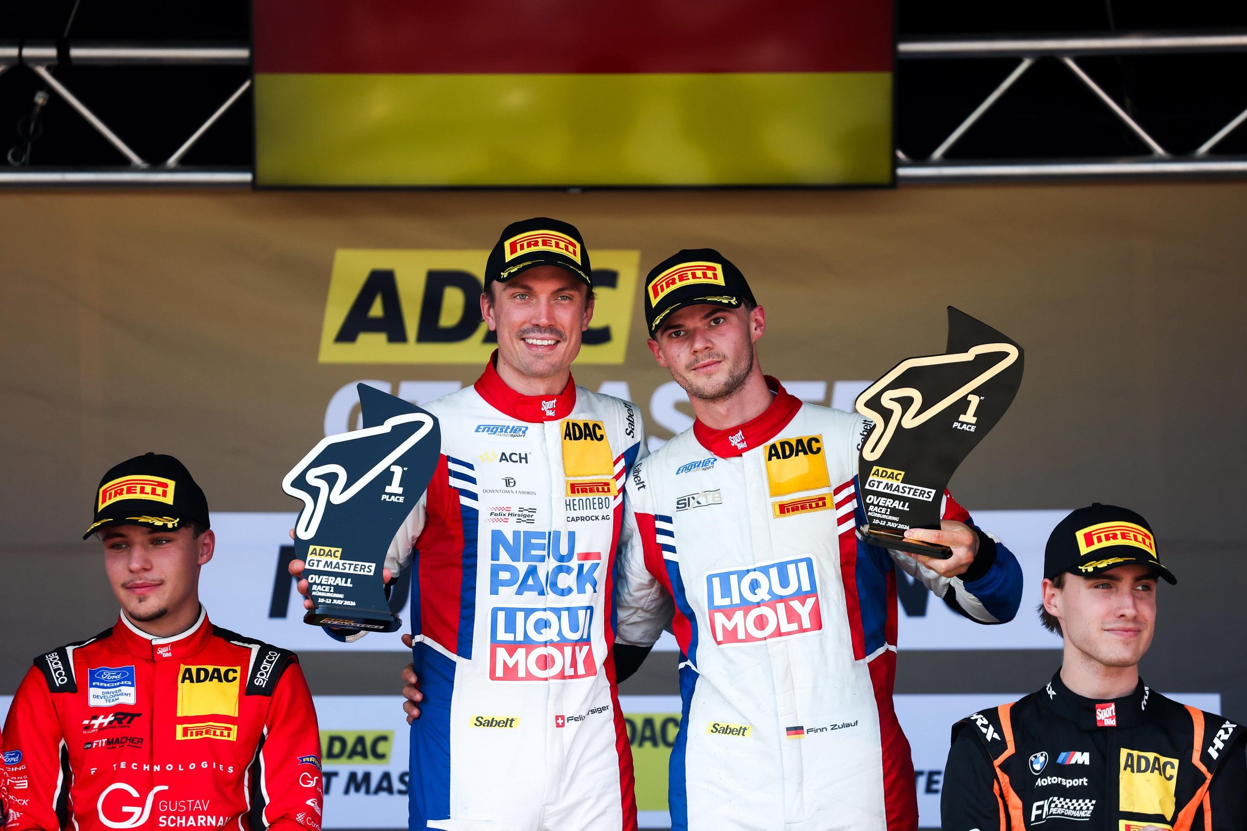 Finn zulauf and felix hirsiger celebrate on the podium with first-place trophies at the nürburgring adac gt masters