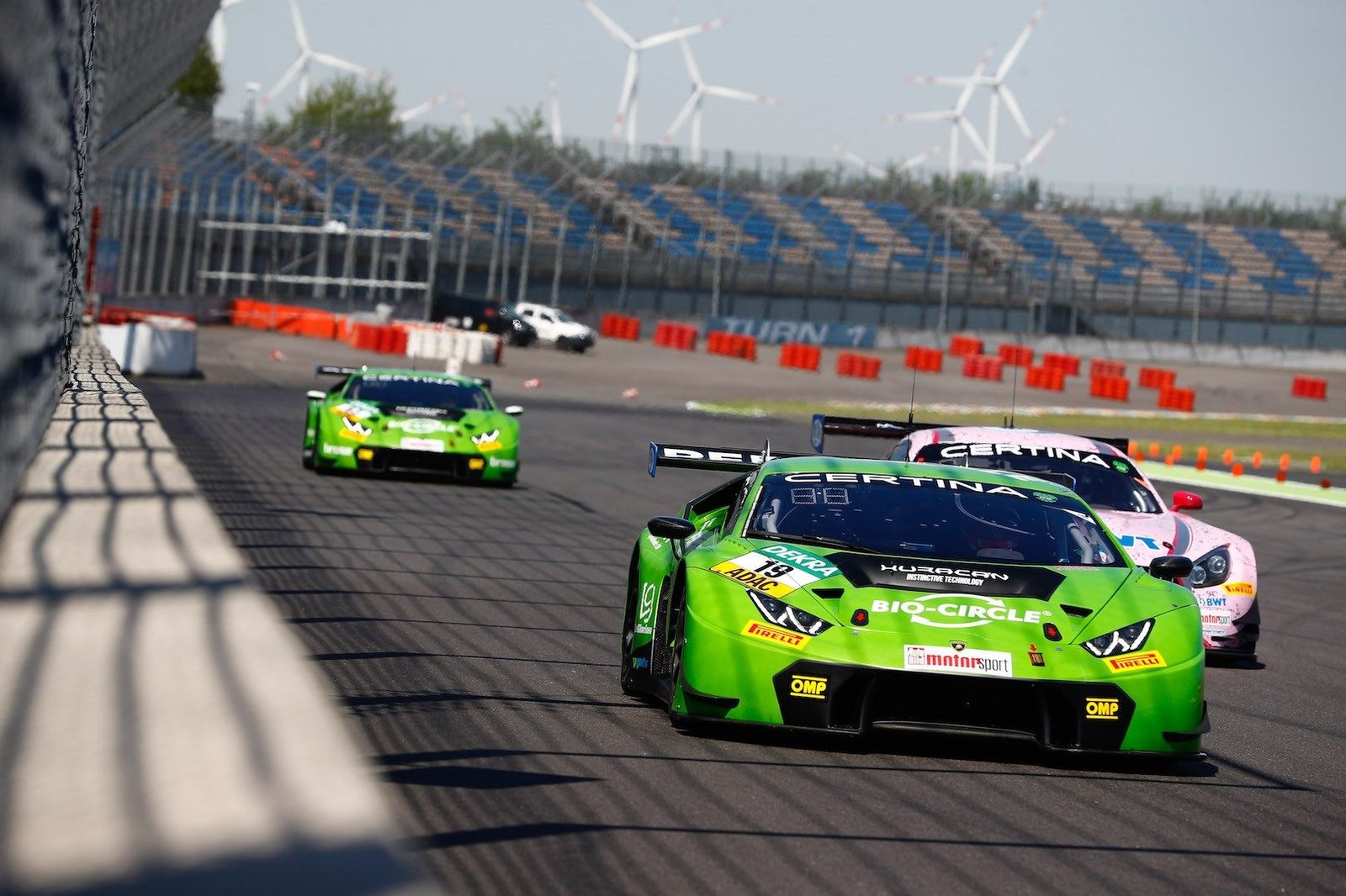 Lamborghini Huracán GT3 in green racing livery leading on track, showing large rear wing and aggressive aerodynamic bodywork