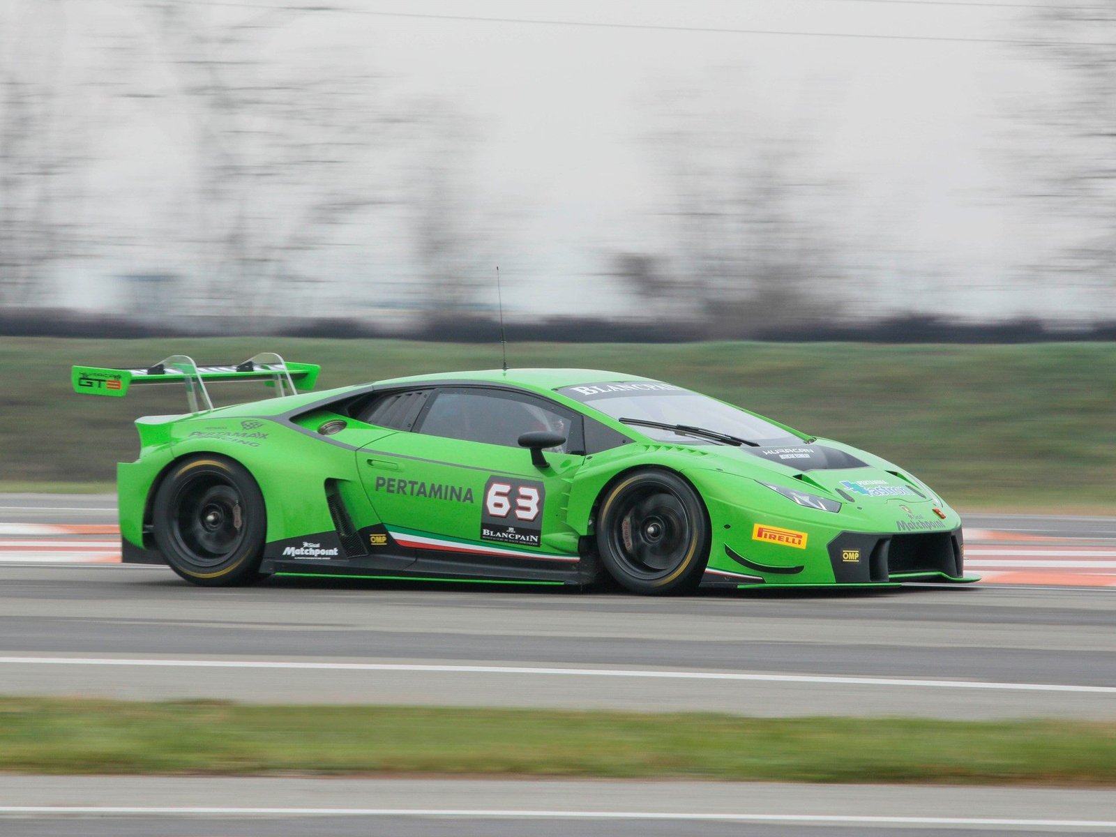 Green Lamborghini Huracán GT3 number 63 at speed on a racetrack with motion blur