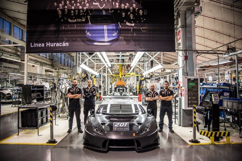 Lamborghini Huracán Super Trofeo on the Sant'Agata Bolognese factory floor with Squadra Corse technicians beneath the Linea Huracán banner