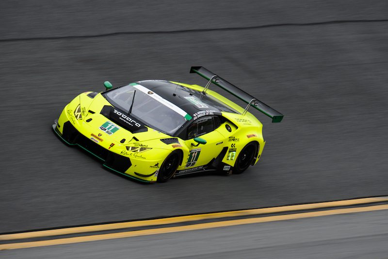 Yellow Lamborghini Huracán GT3 number 11 racing on a wet Daytona track from an elevated perspective