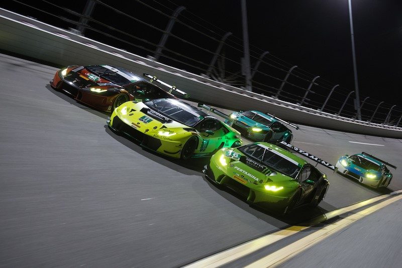 Multiple Lamborghini Huracán GT3 race cars battling on the Daytona track at night under bright track lights