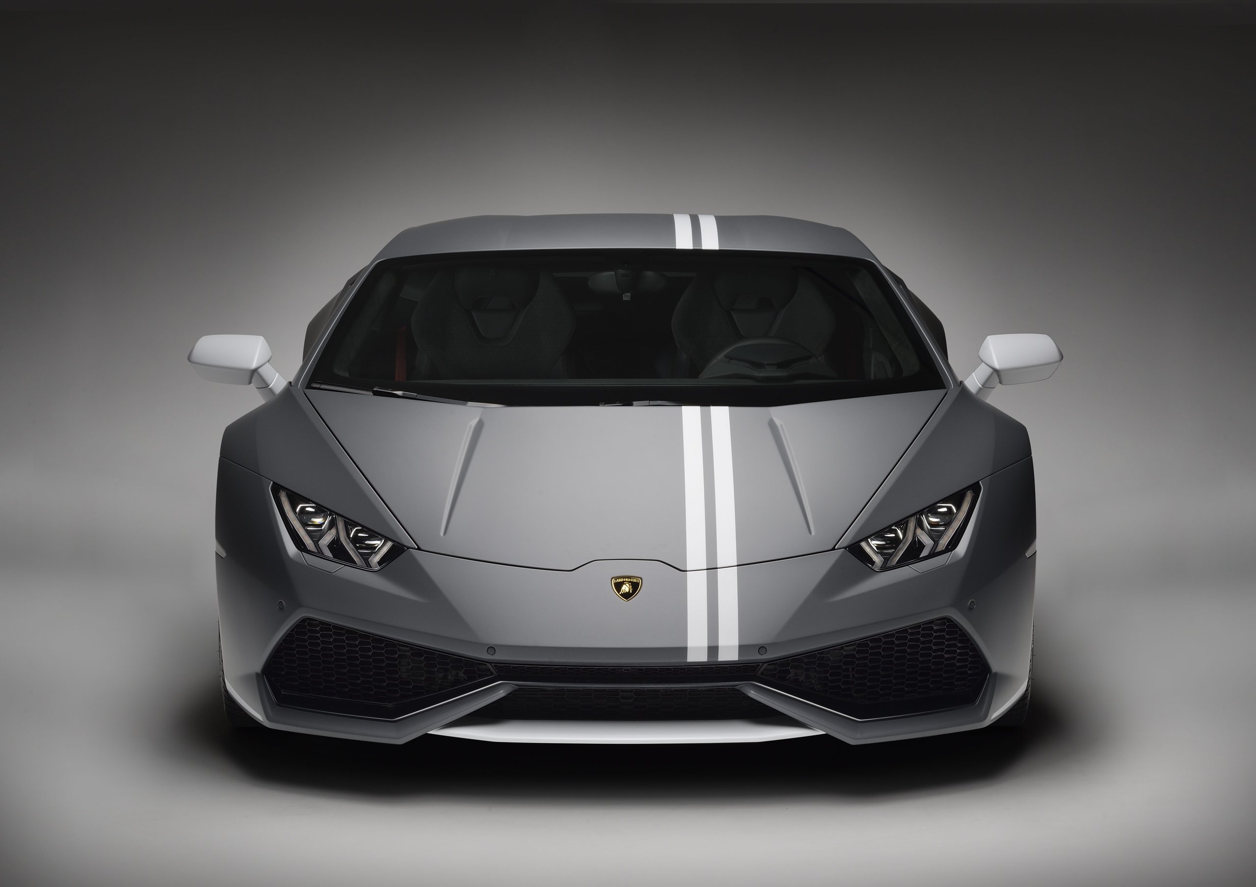 Grey Lamborghini Huracán with white racing stripes shown head-on, highlighting Y-shaped LED lights and large front air intakes