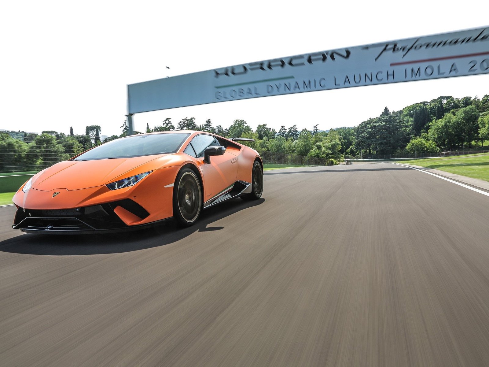 Orange Lamborghini Huracán Performante at speed on a racetrack with motion blur in the background