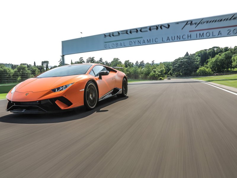 Orange Lamborghini Huracán Performante at speed on a racetrack with motion blur in the background