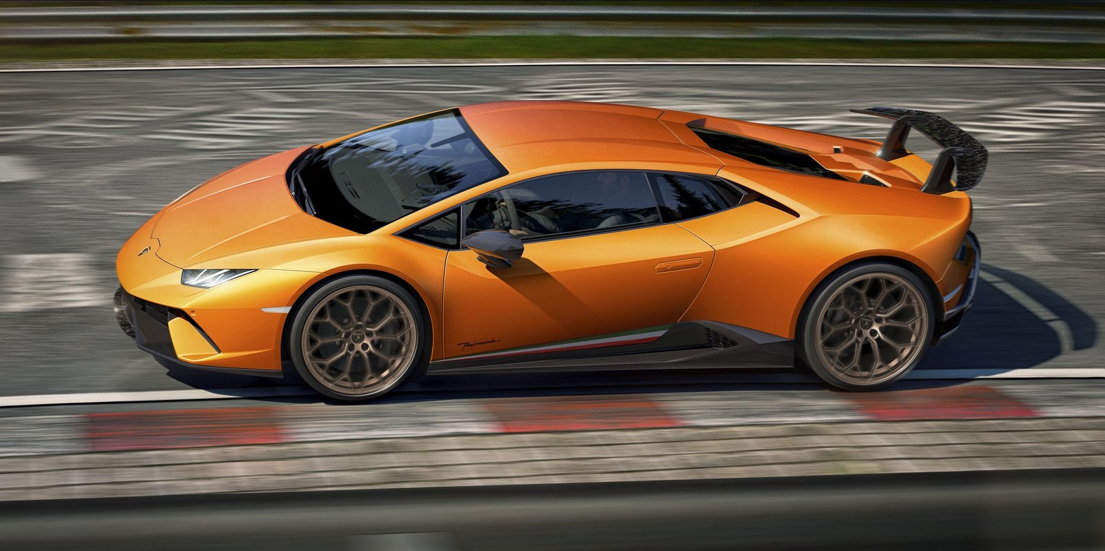 Orange Lamborghini Huracán Performante at speed on a race track, showing its prominent rear wing and bronze wheels